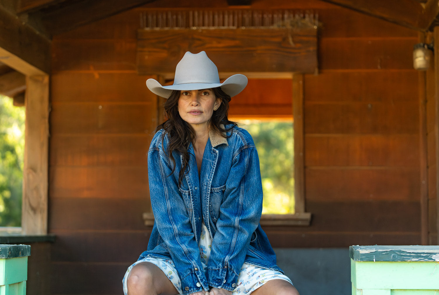 A diverse group of people wearing various styles of cowboy hats in a picturesque outdoor setting with rolling hills and a clear blue sky, engaged in activities like hiking, boating, and gardening.