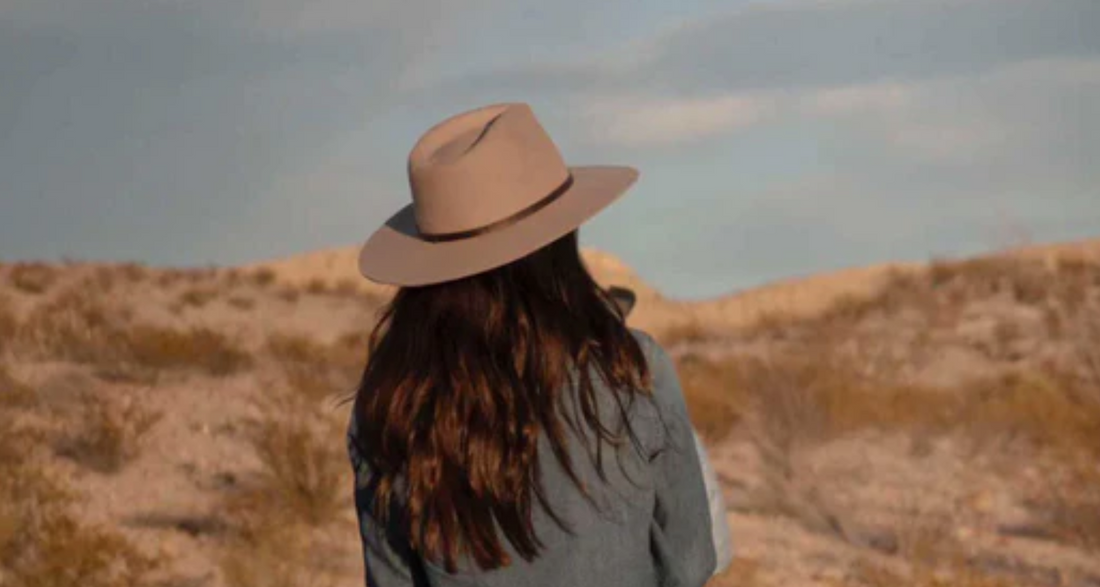 a woman wearing a beige wool hat looks into the distance.