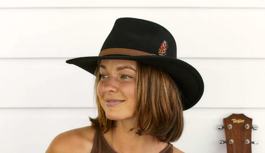 woman wears a black wool cowboy hat with a feather on the band.