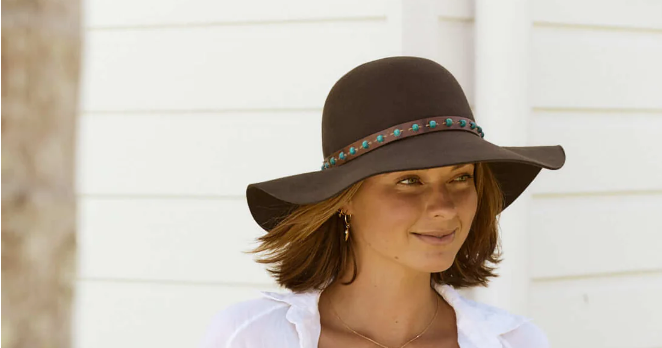 Woman walks while wearing a brown floppy wool hat with a beaded band