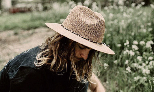 Man with long hair wearing a straw fedora hat
