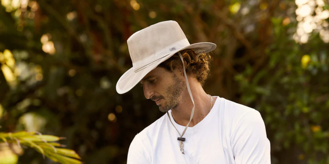 man wearing a white sailing hat and white T-shirt looks down