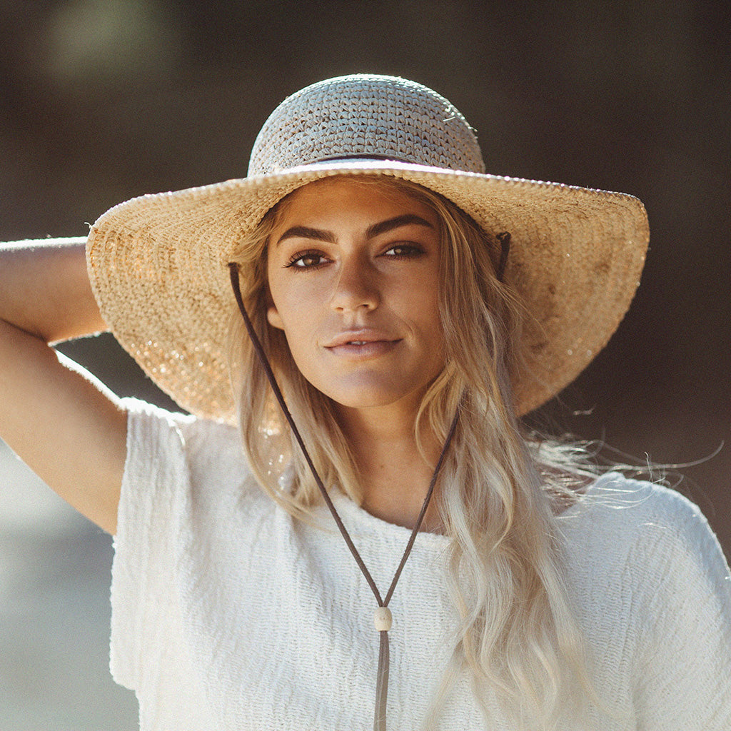 Woman wearing Latin Quarter ladies raffia wide brim straw hat with chin cord