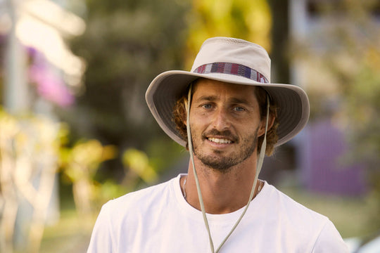 Man outside wearing cloth recycled boating sailing hat in color Sand showing chin cord 