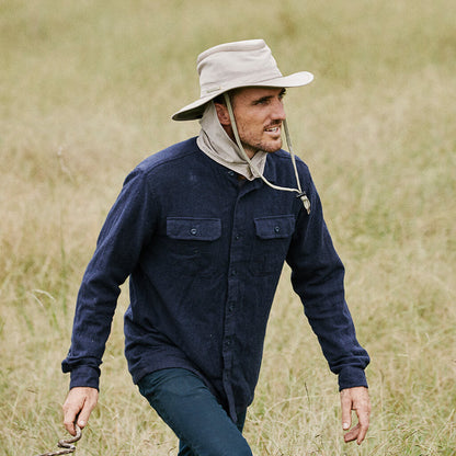 Man walking outside in field wearing Boating or sailing hat with sun shield that goes into brim and chin cord in color Sand