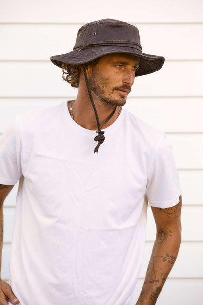 Man in white T shirt wearing Dusty Road Conner Hats cloth waterproof bucket or boonie style hat with a chincord