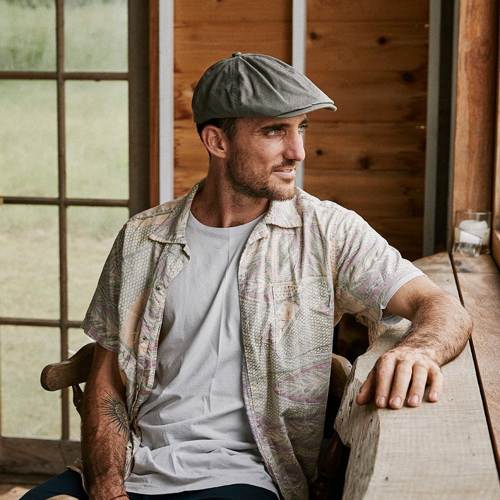 Man sitting in cabin wearing Conner hats organic cotton newsboy golf hat in color Olive