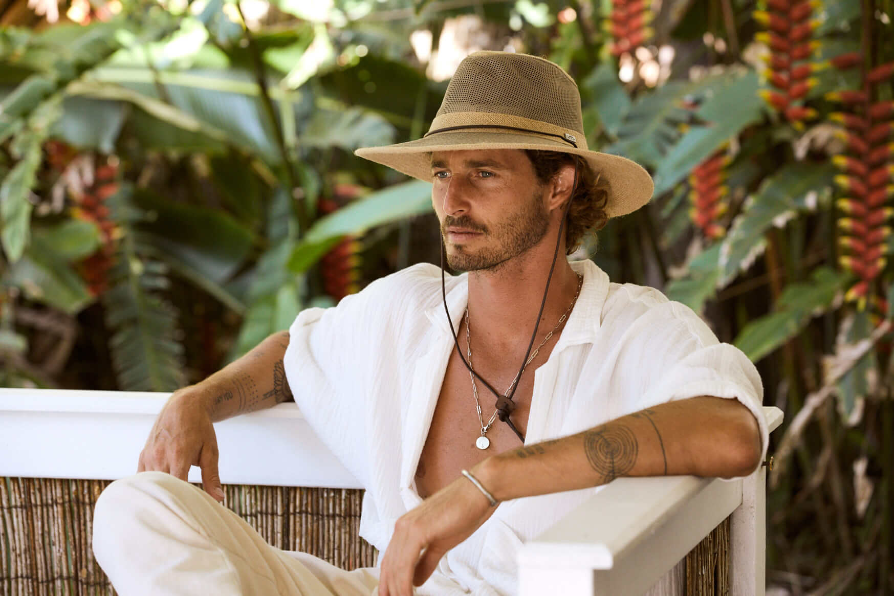Man sitting in tropical setting wearing Conner Hats Cool Air Hiker hat made from hemp cloth with mesh crown and chin cord