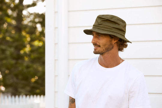 Man outside in yard wearing Conner Hats organic cotton cloth bucket hiking hat in color Olive