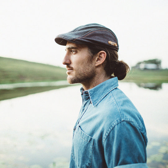 Man outside near lake wearing cotton Newsboy Flat Cap with leather accent and buttons