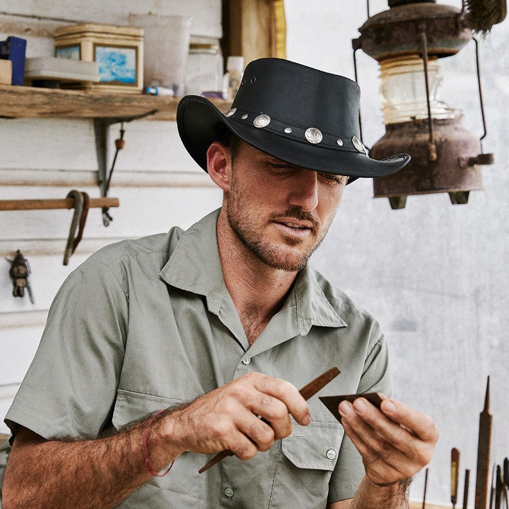 Man in workshop wearing Black leather outback hat with buffalo nickel coins around the band