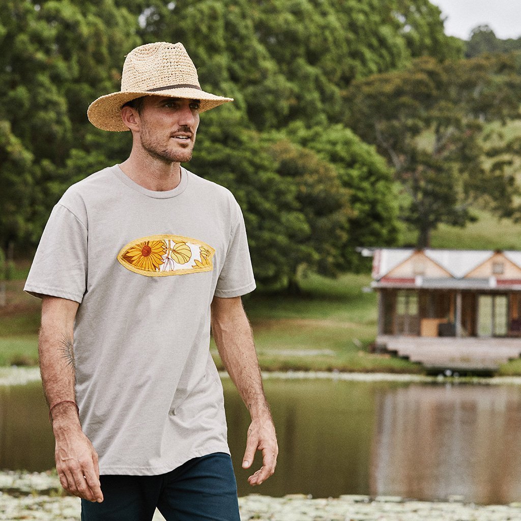 Man walking outside near lake wearing hand crocheted raffia straw sun hat with brown faux leather band