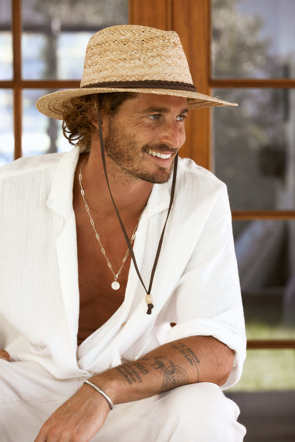 Man smiling wearing straw outback sun hat with faux leather braided hat band and chin cord
