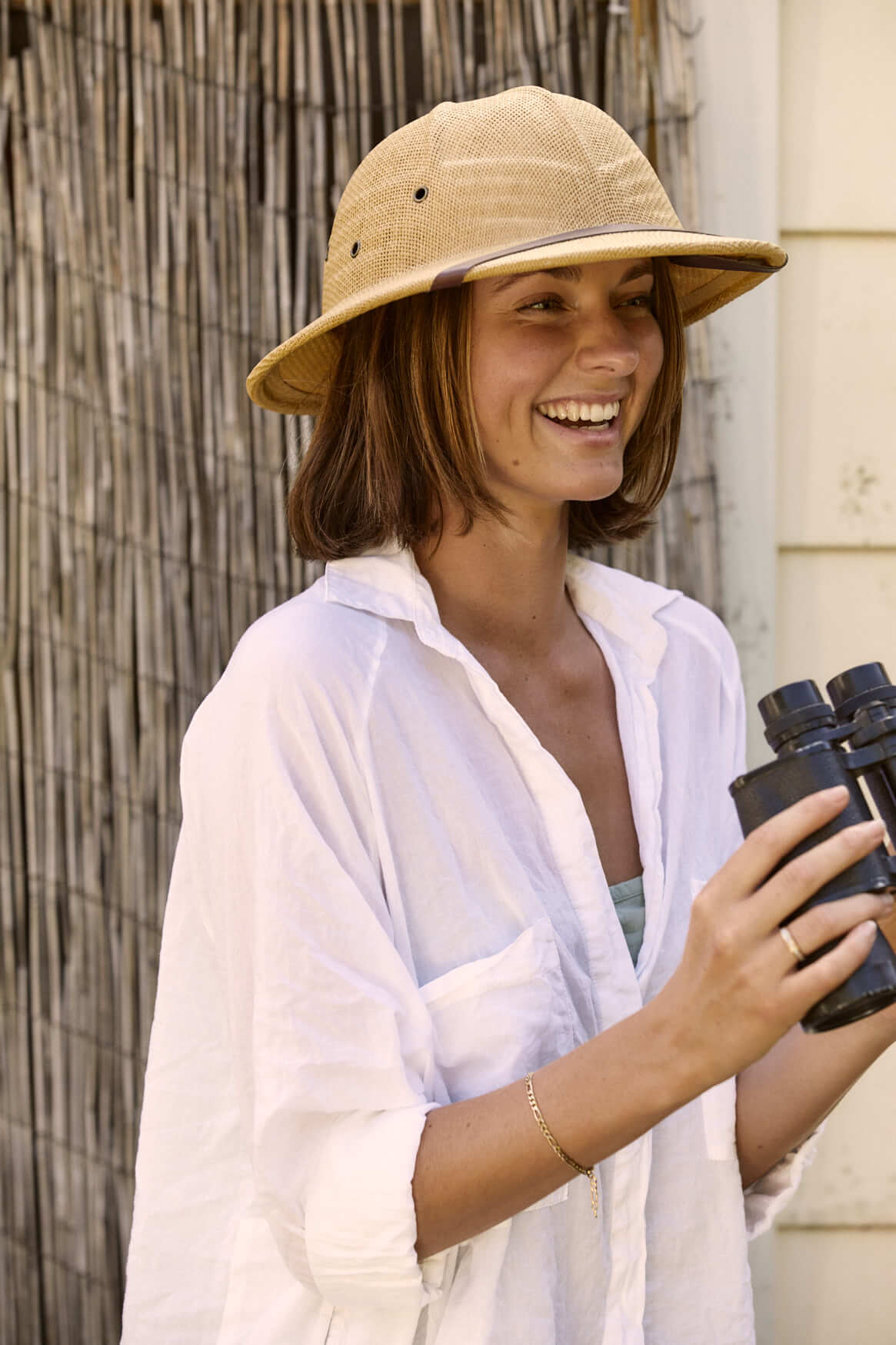 Woman laughing with binoculars wearing straw Safari Pith Helmet with three eyelets