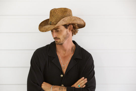 Man in western shirt wearing Conner Hats Country Western straw hat hand braided from raffia in Brown color with faux leather band and brass colored star and conchos