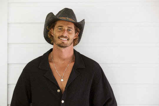 Man smiling wearing Conner Hats Country Western straw hat hand braided from raffia in Black color with faux leather band and brass colored star and conchos