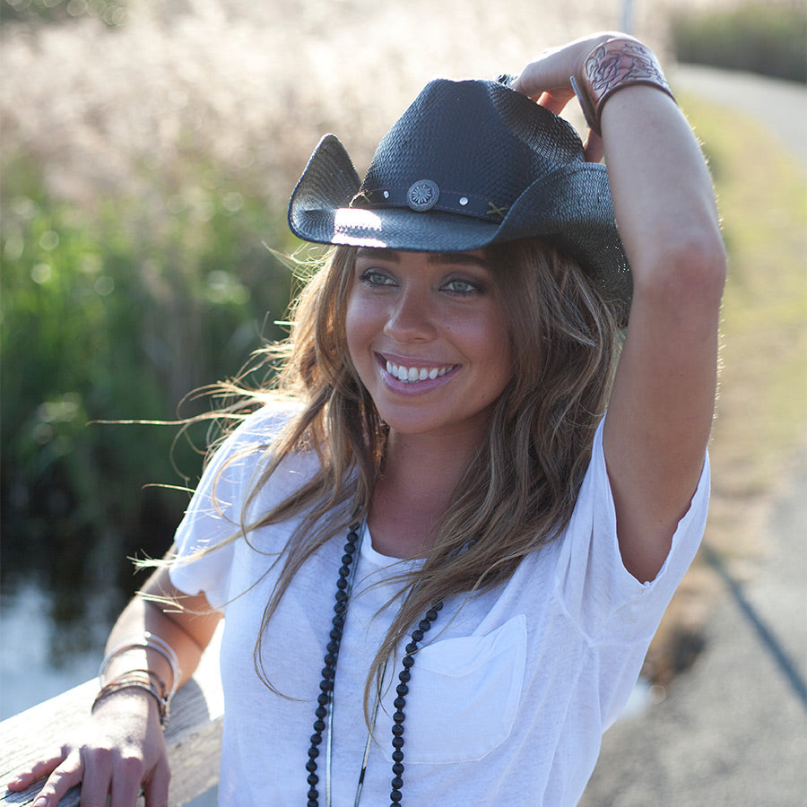 Woman outside wearing western straw hat in color Black with silver conch and faux leather band