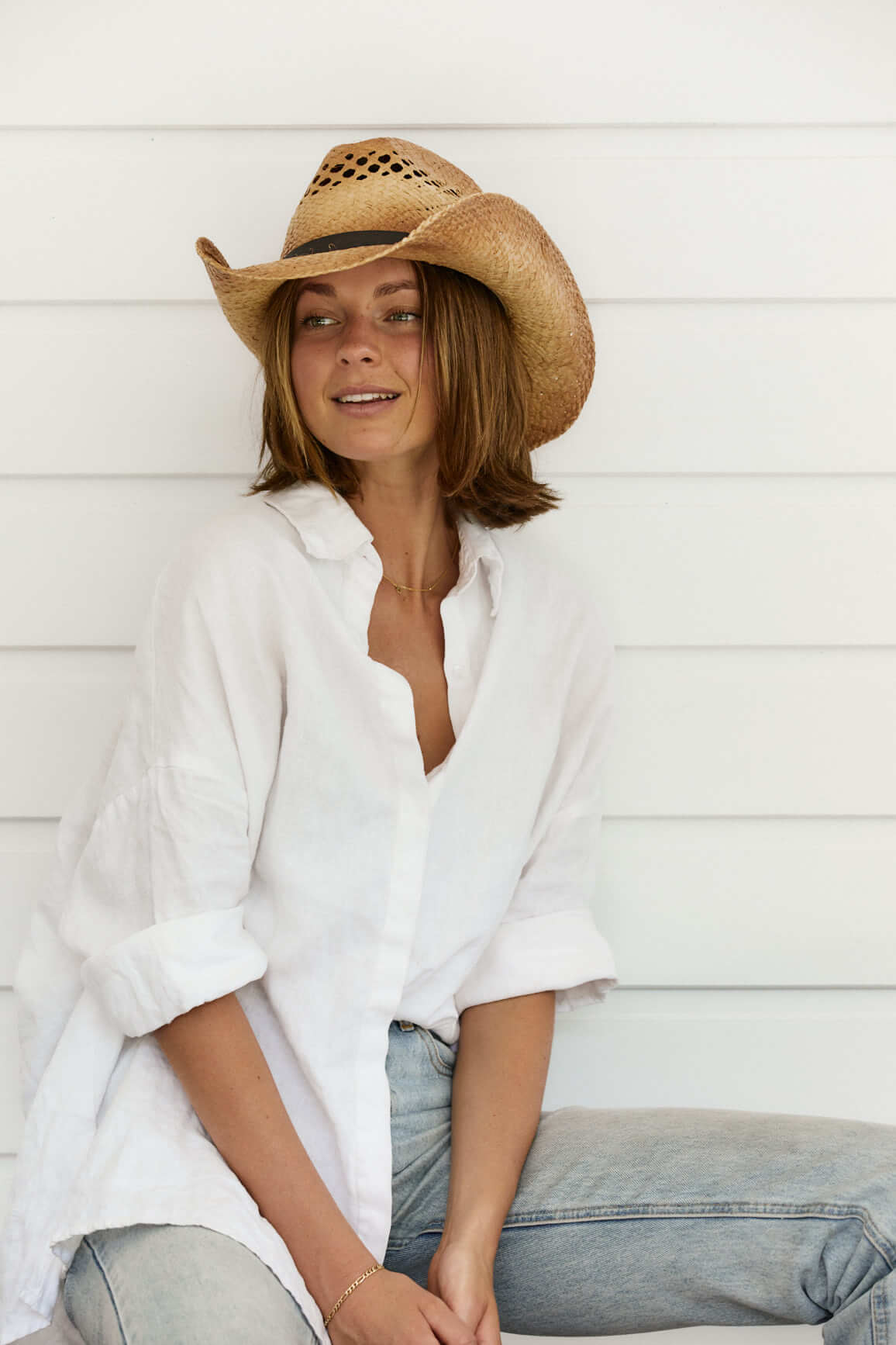 Woman in White shirt wearing western straw hat with vented crown and route 66 logo on vegan hat band