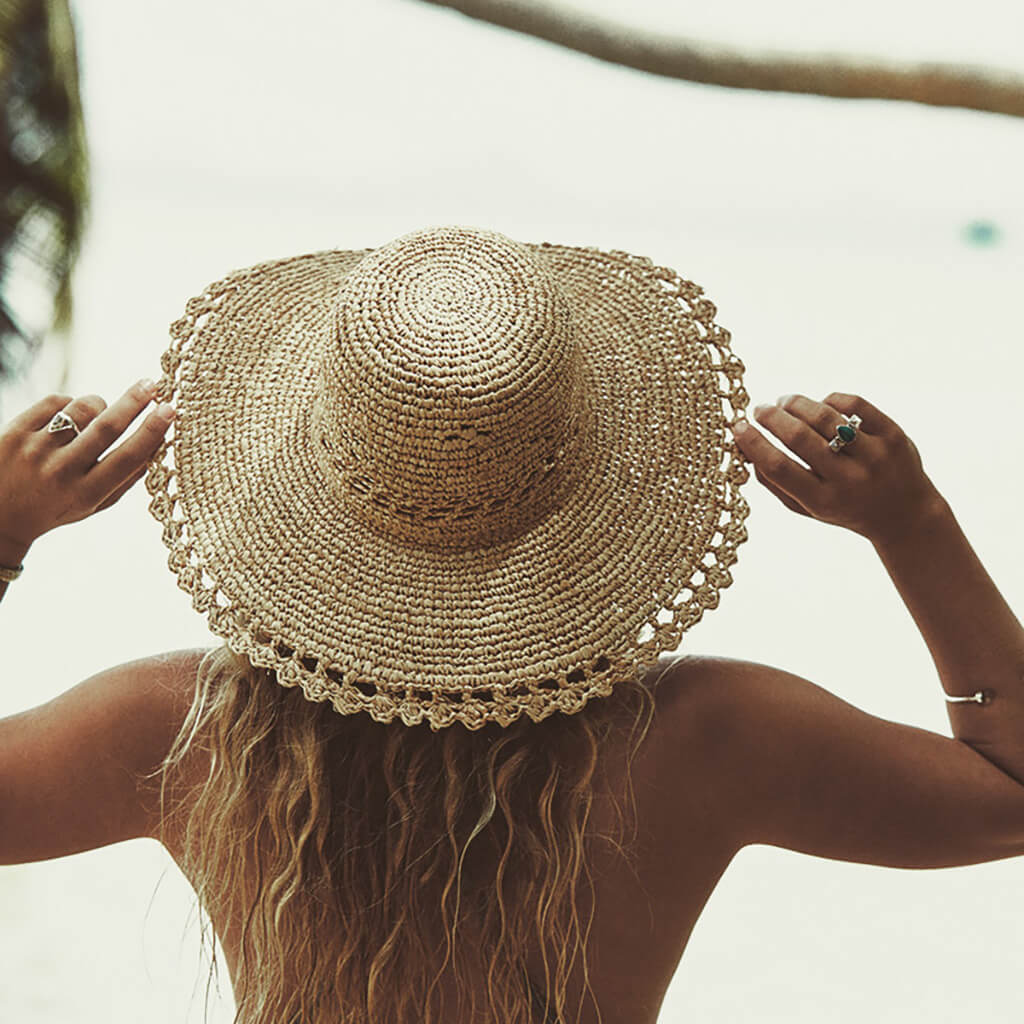 Staring out to sea in Women's raffia straw wide brim hand crocheted summer hat with an open weave vent in crown and edge