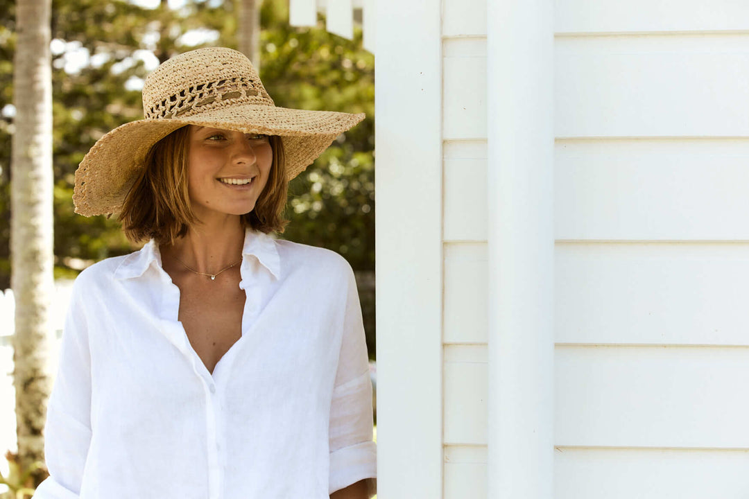 Standing outside in Women's raffia straw wide brim hand crocheted summer hat with an open weave vent in crown and edge