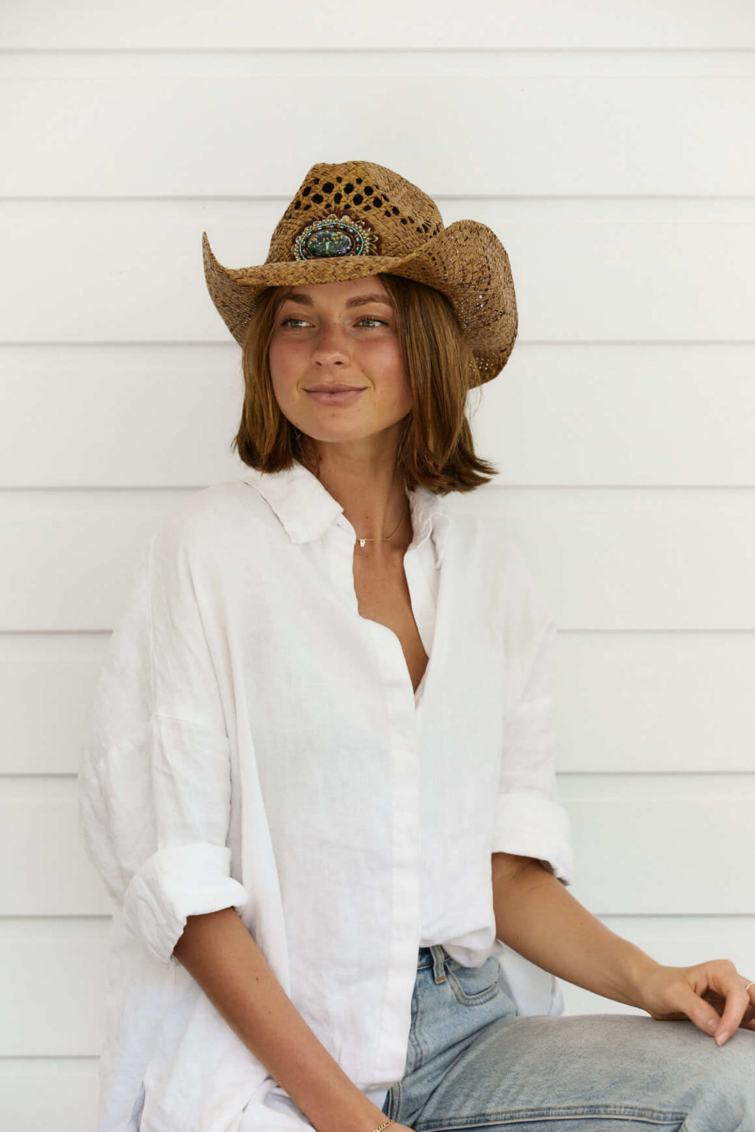 Woman wearing raffia straw western women's hat with vented crown and beautiful beaded feather concho