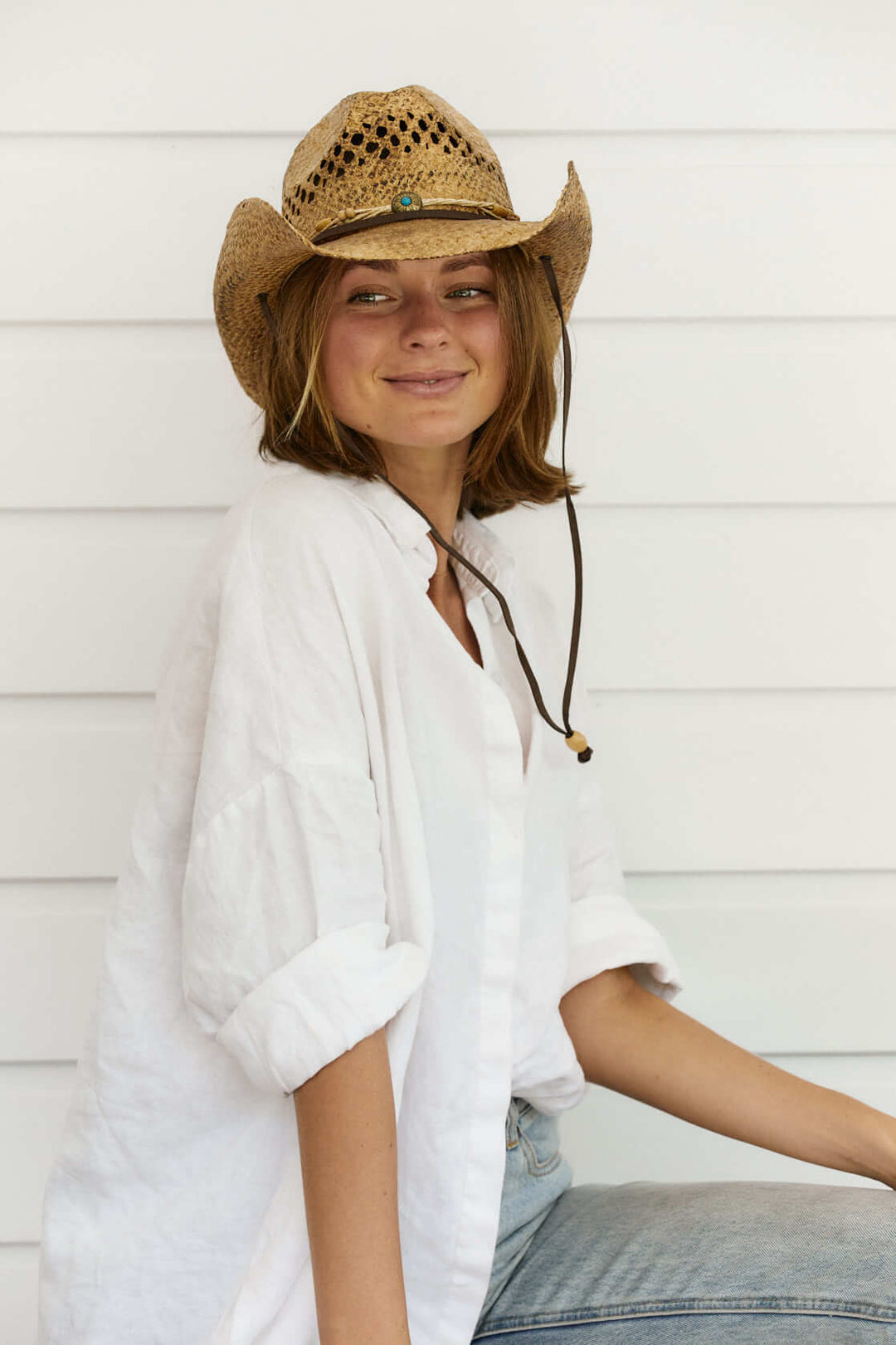 Woman wearing straw western raffia hat with vented crown and chin cord