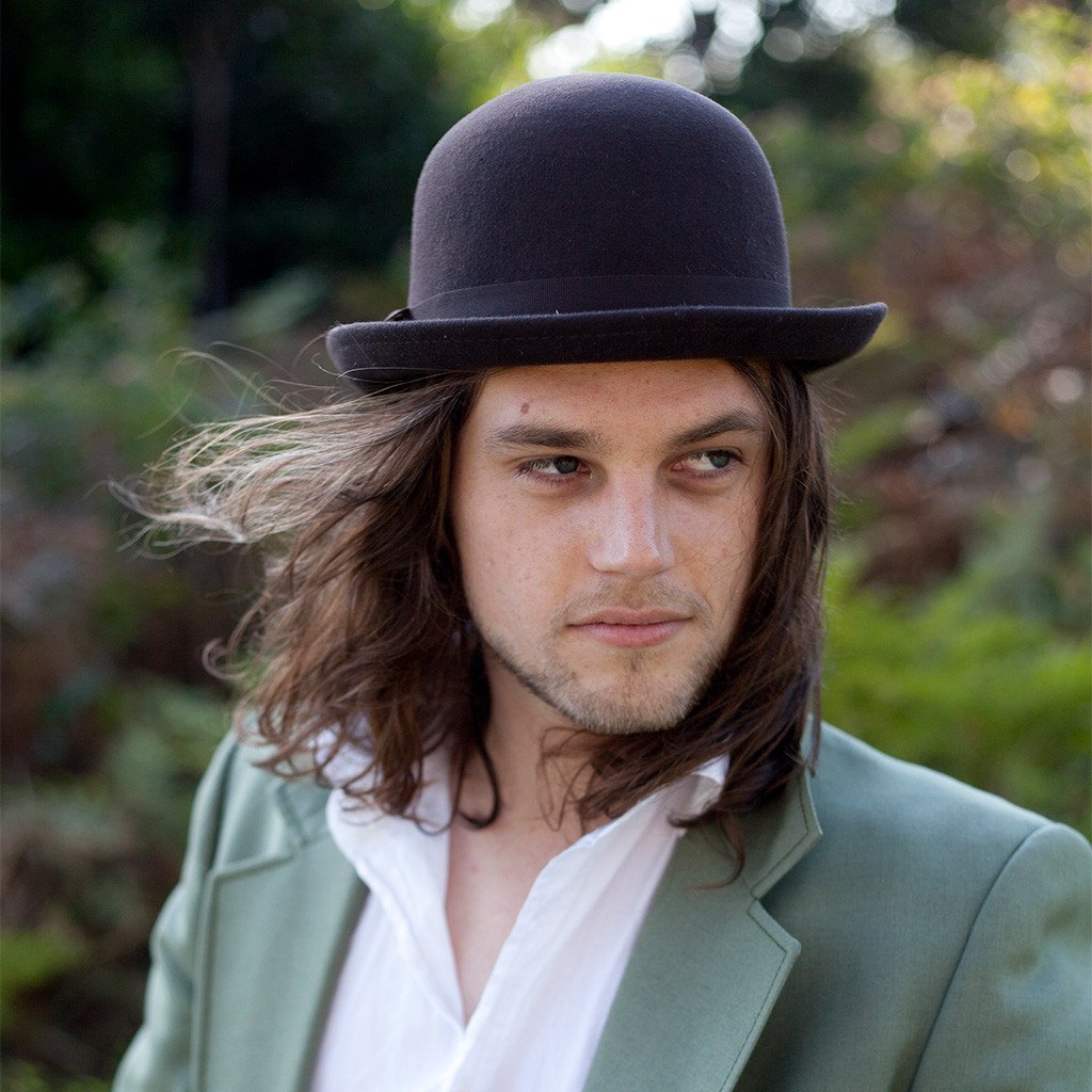 Man standing outside in Green suit wearing wool hat bowler/derby in color Black