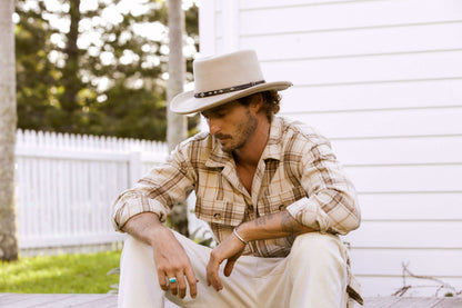 Man sitting outside in Putty wool gambler hat with vegan band with silver colored studs