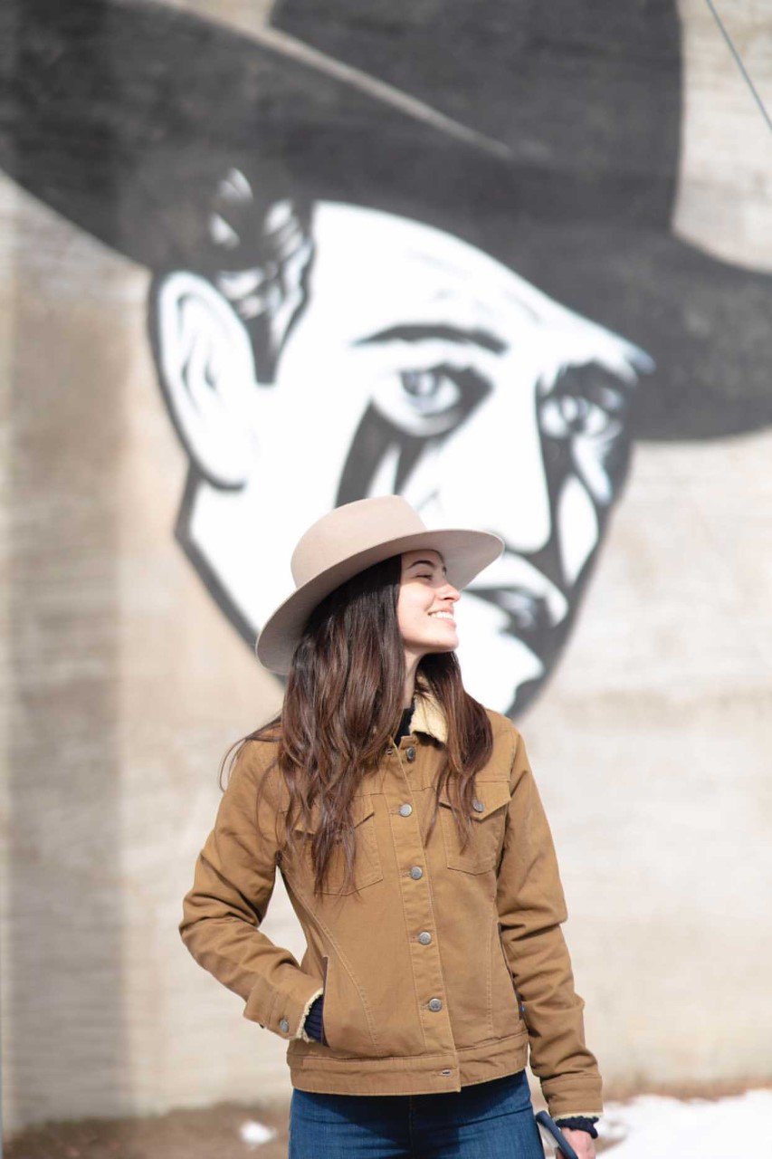 Woman in stiff raw edge western outback wool hat with wide flat brim in Putty color with dark leather band