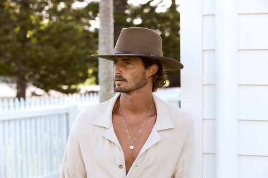 Man outside in stiff raw edge western outback wool hat with wide flat brim in Brown color with dark leather band