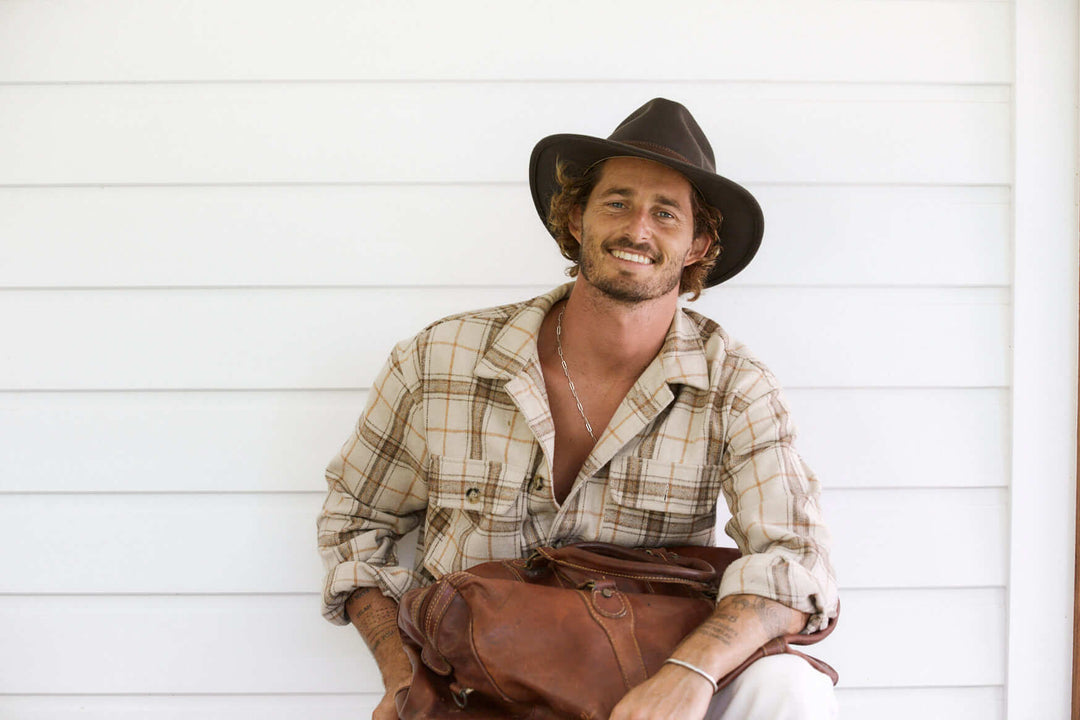 Man holding a duffel bag wearing Conner Hats Flinders outback wool Australian style Hat with a stitched faux leather hat band