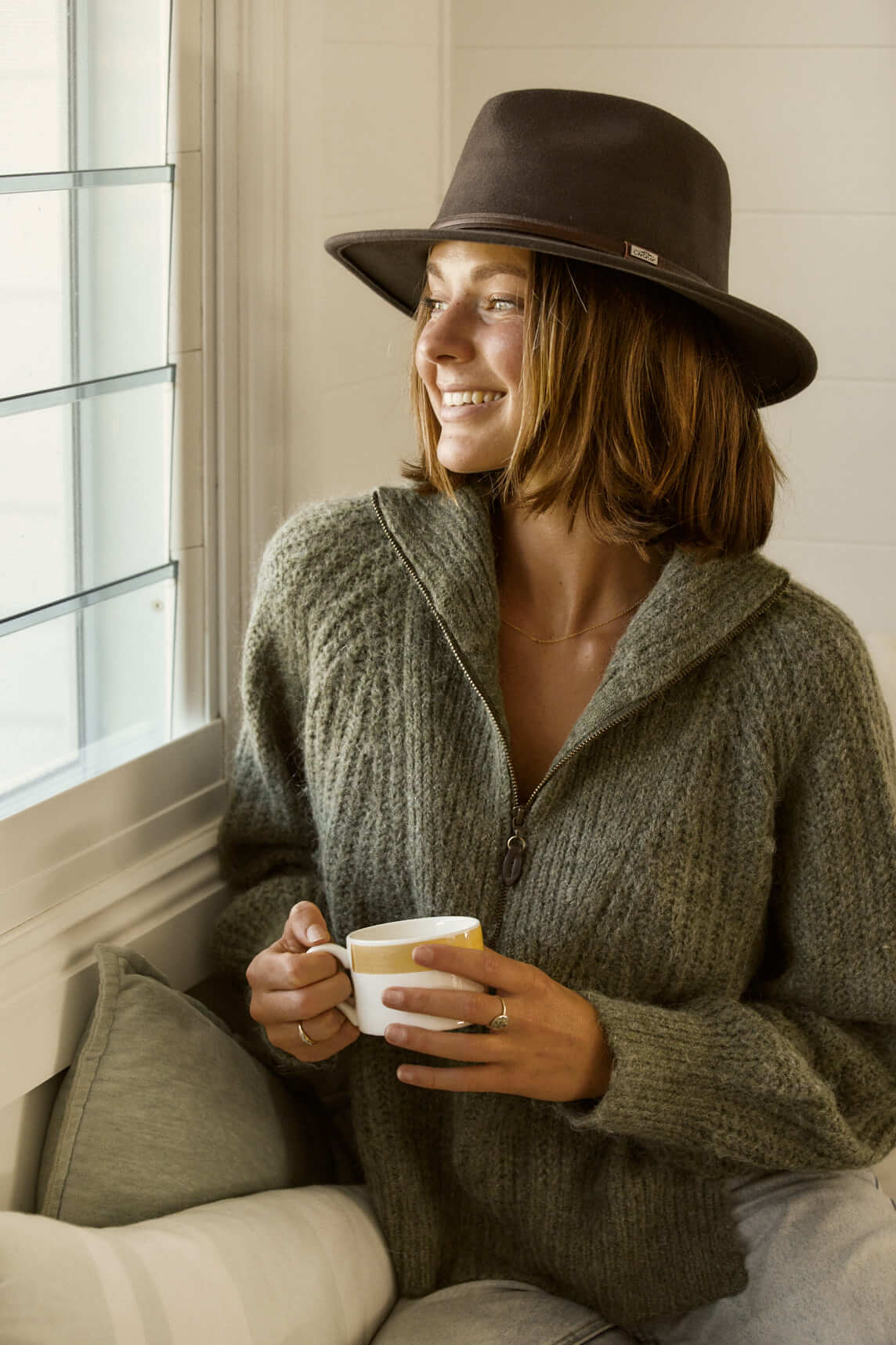 Woman in sweater drinking tea  wearing Conner Hats Jackeroo crushawool outback Australian style Hat in color Brown with smooth leather hat band and Conner Emblem