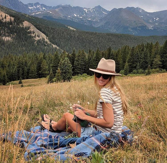 Woman sitting outside on a blanket wearing Putty colored Wide Open Spaces Outback hat