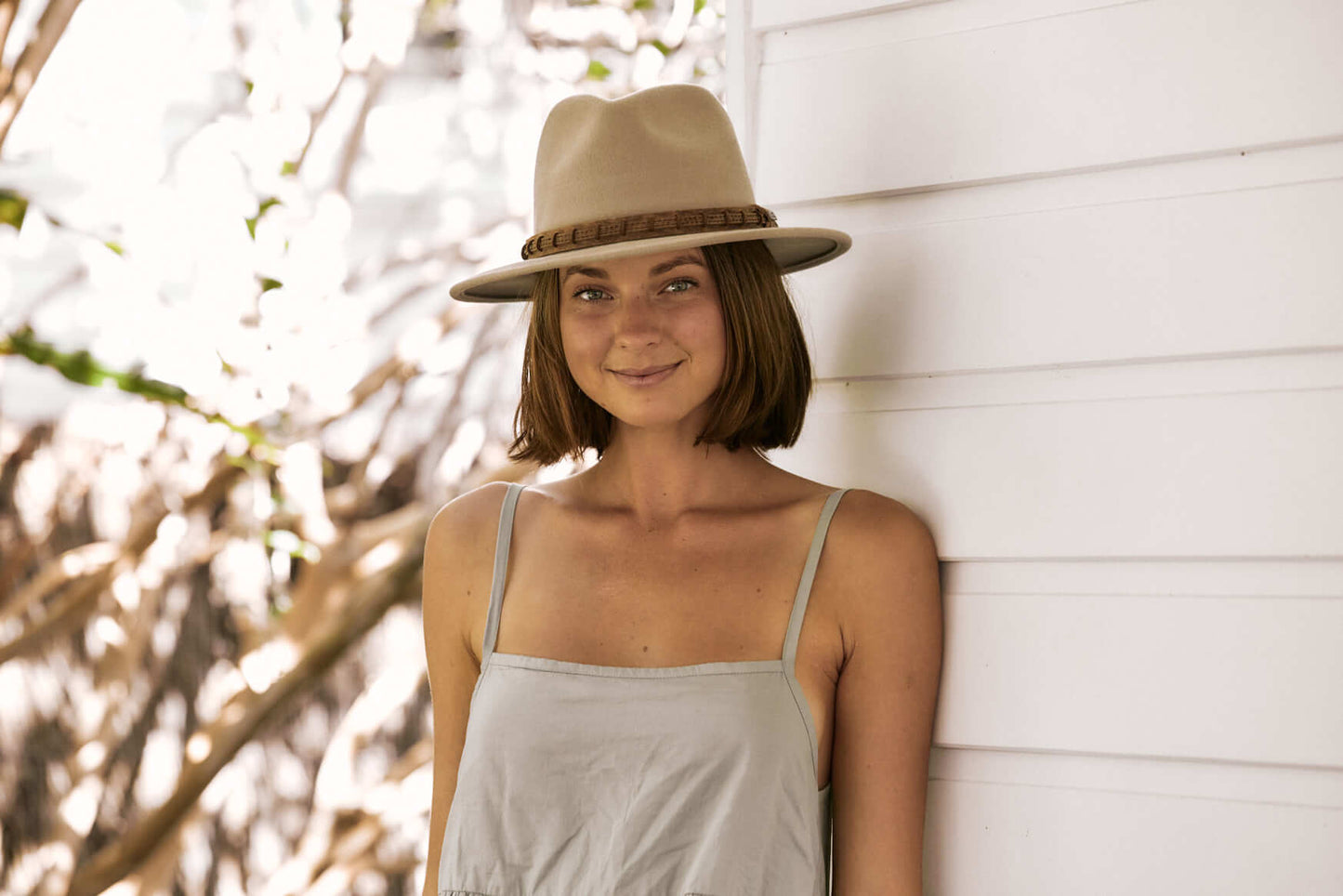Woman standing outside smiling wearing outback wool hat in color Putty with leather hat band