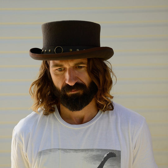 Man with long hair wearing wool Steampunk top hat with brass ring and chain