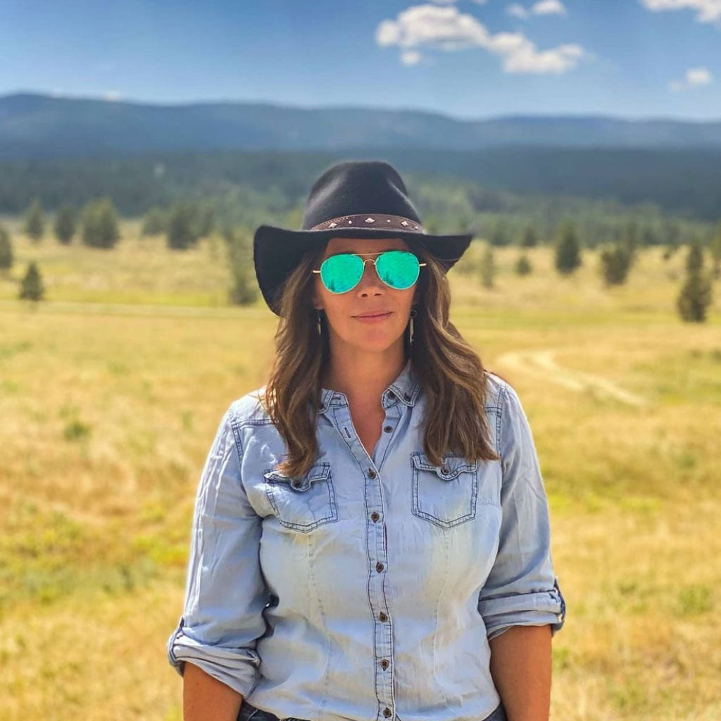 Woman outside in sunglasses wearing Yellowstone western wool hat hat in color Black featuring an embossed leather band with silver conchos