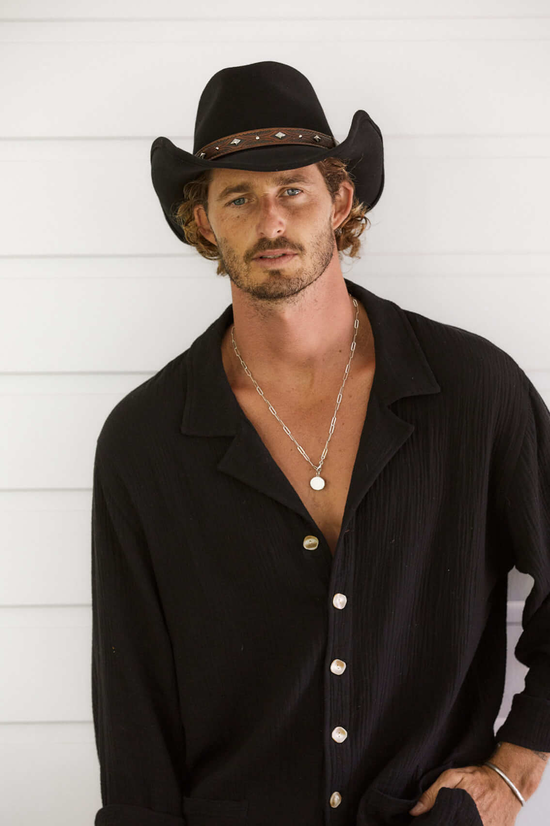 Man looking at camera in western shirt wearing Yellowstone western wool hat hat in color Black featuring an embossed leather band with silver conchos