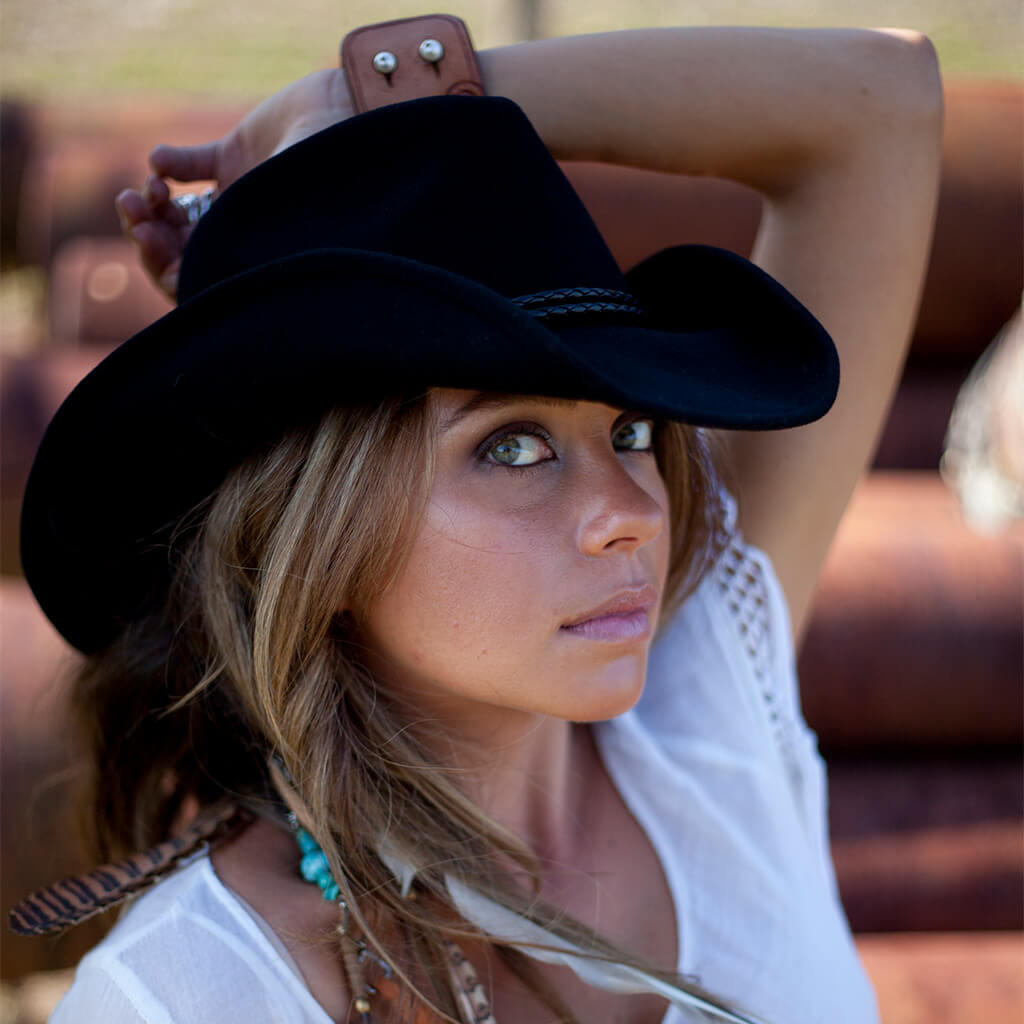 Woman on a farm wearing western wool hat with shapable brim and braided hat band